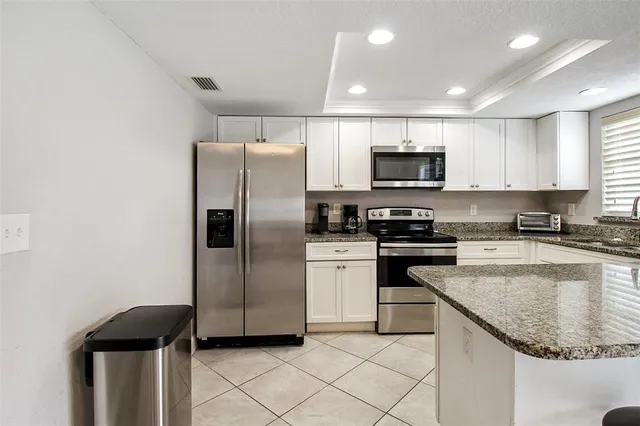 a kitchen with granite countertop a refrigerator and a stove top oven