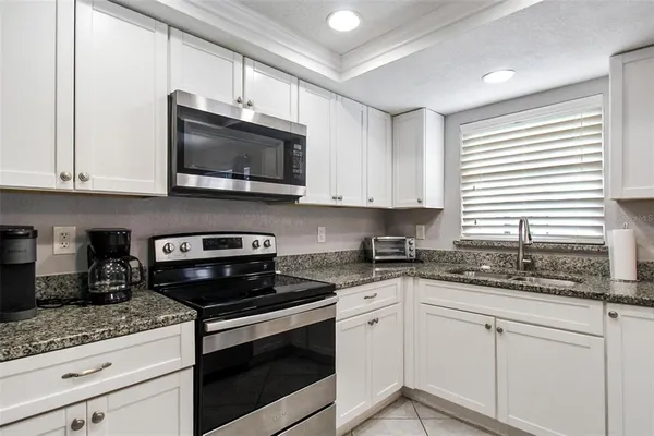 a kitchen with stainless steel appliances granite countertop white cabinets granite counter tops and a wooden floors