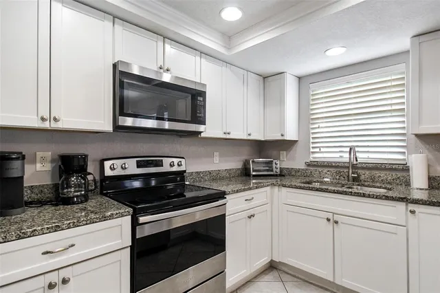 a kitchen with stainless steel appliances granite countertop white cabinets granite counter tops and a wooden floors