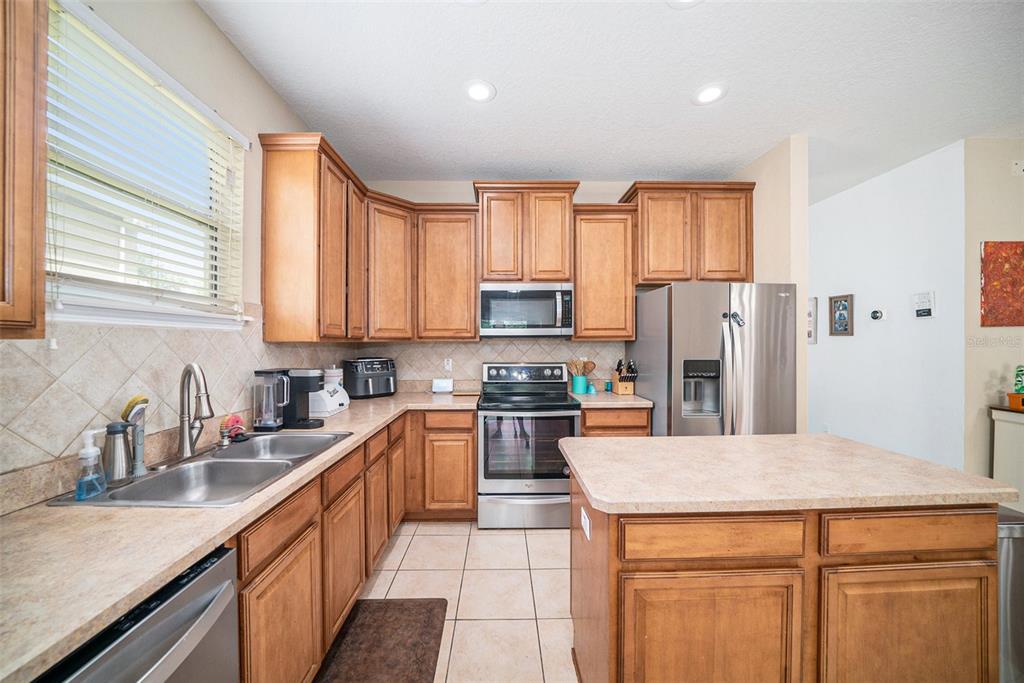 12045 Colony Lakes Boulevard New Port Richey, FL 34654 - Photo 3 of 22 a kitchen with stainless steel appliances granite countertop a refrigerator a sink dishwasher a stove with large countertops and wooden cabinets