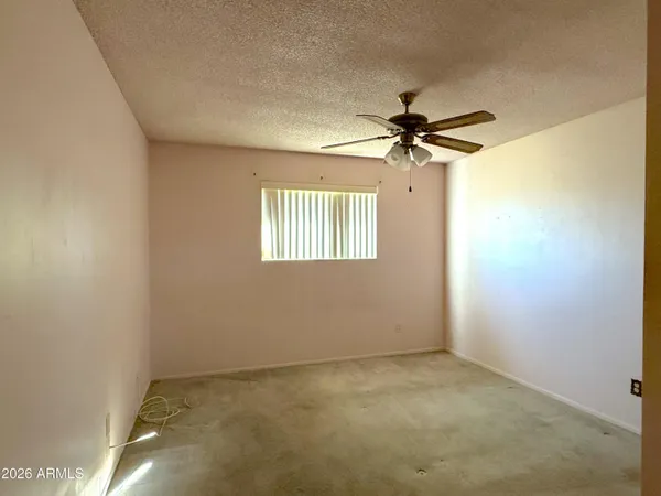 an empty room with a chandelier fan and windows