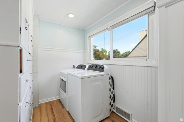 210 North 200 West Logan, UT 84321 - Photo 16 of 31 Laundry area featuring a large window, wood-finish flooring, beadboard wainscoting, and built-in cabinetry with drawer and cabinet storage