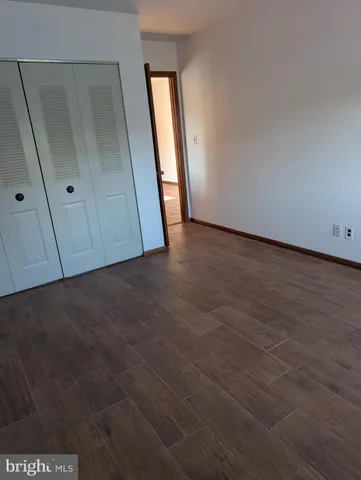 a view of an empty room with wooden floor and closet