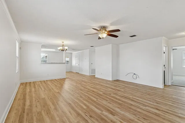 a view of empty room with wooden floor and ceiling fan