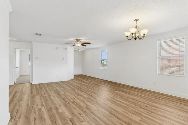 a view of empty room with wooden floor and ceiling fan