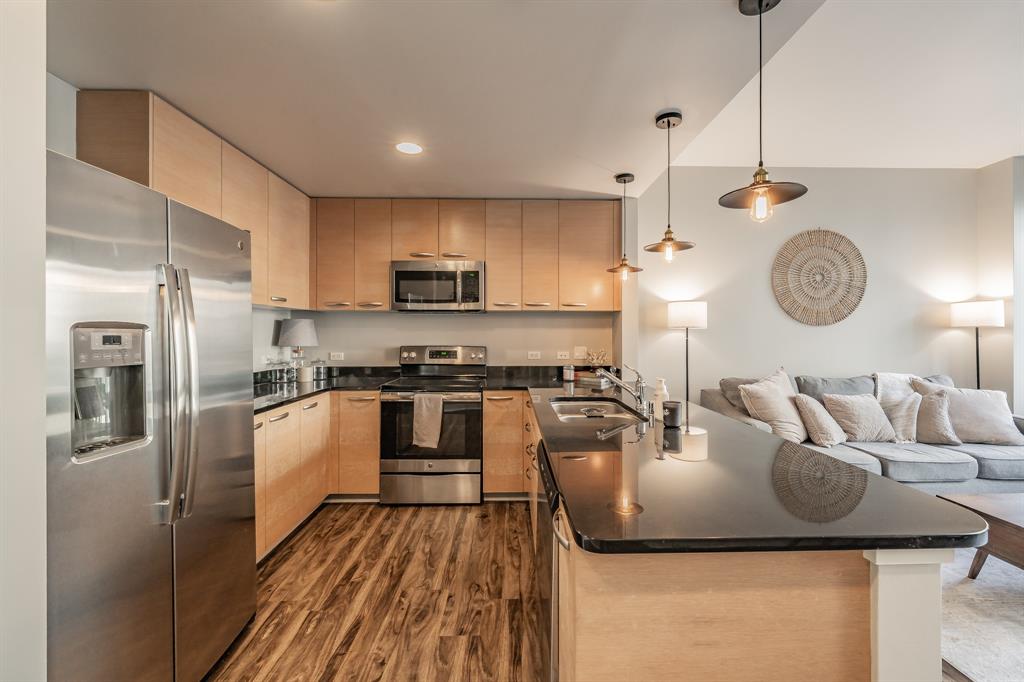 1200 Main Street, Unit 812 Dallas, TX 75202 - Photo 4 of 17 a kitchen with kitchen island granite countertop a sink a stove top oven a refrigerator cabinets and living room view