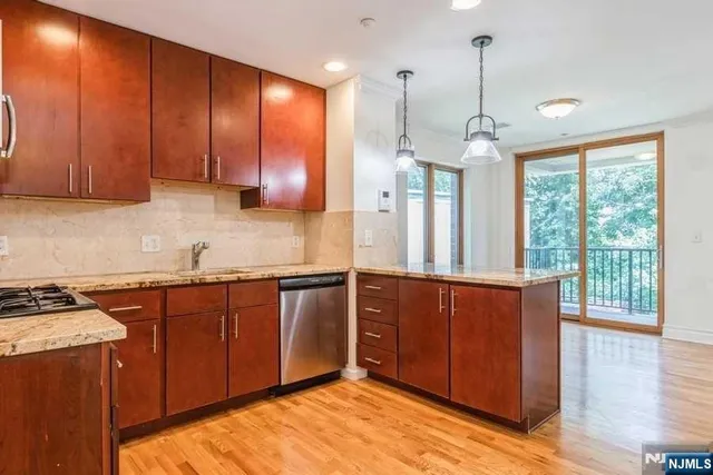 a kitchen with stainless steel appliances granite countertop wooden cabinets a stove a sink and a large window