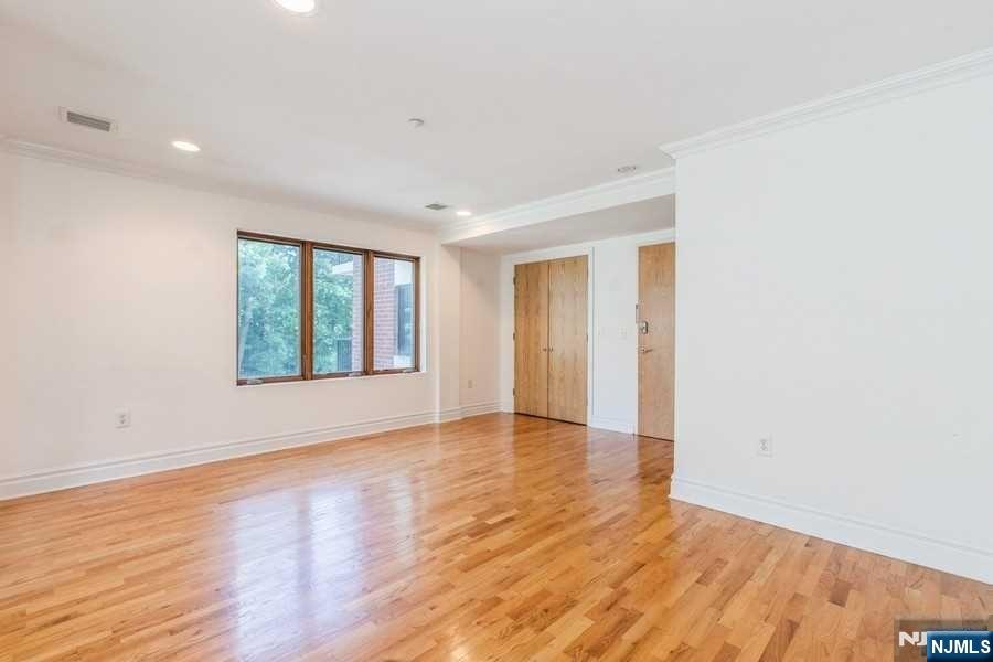 17 Meadow Road, Unit 301 Rutherford, NJ 07070 - Photo 7 of 21 a view of an empty room with wooden floor and a window