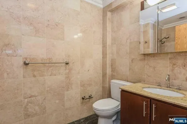 a bathroom with a granite countertop sink a toilet and shower