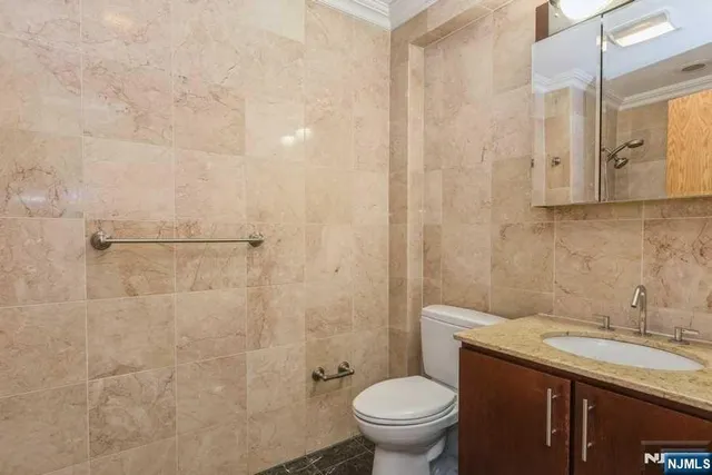 a bathroom with a granite countertop sink a toilet and shower