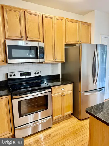 a kitchen with granite countertop a refrigerator stove and microwave