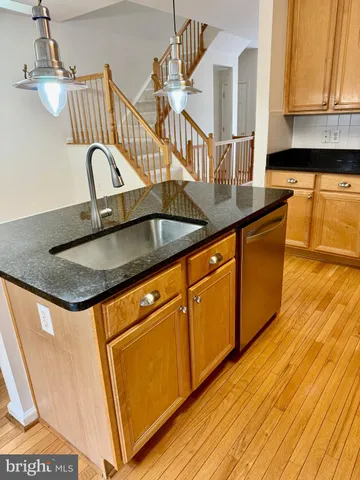 a kitchen with granite countertop a sink a stove and cabinets with wooden floor