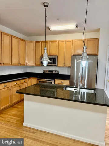a kitchen with kitchen island granite countertop a sink appliances and cabinets