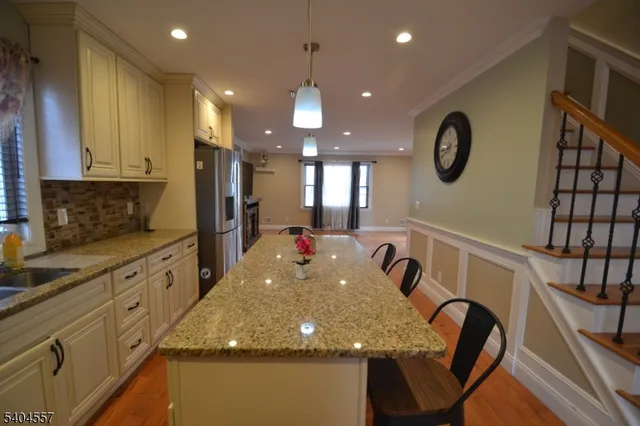 a kitchen with kitchen island granite countertop a stove a sink a microwave a dining table and chairs with wooden floor