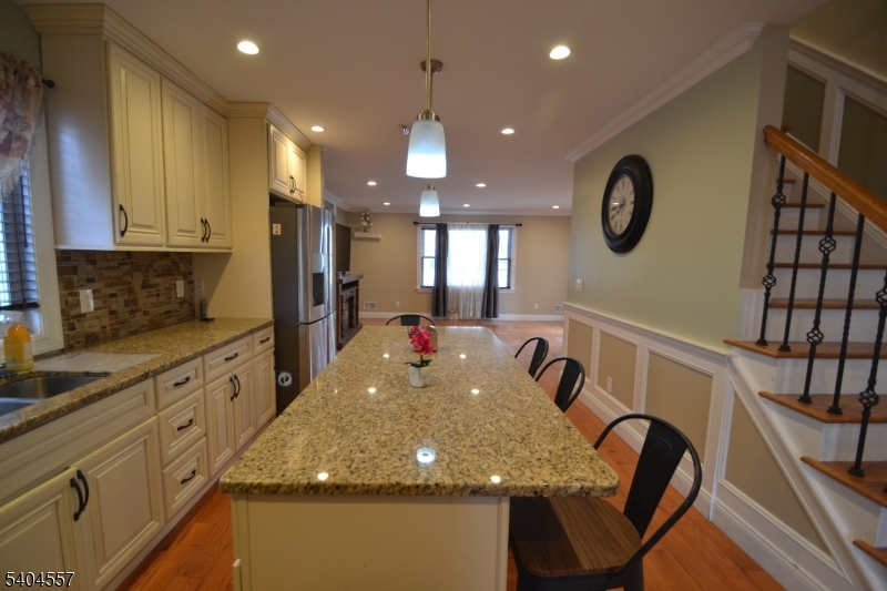 204 Market Street Garfield, NJ 07026 - Photo 14 of 36 a kitchen with kitchen island granite countertop a stove a sink a microwave a dining table and chairs with wooden floor