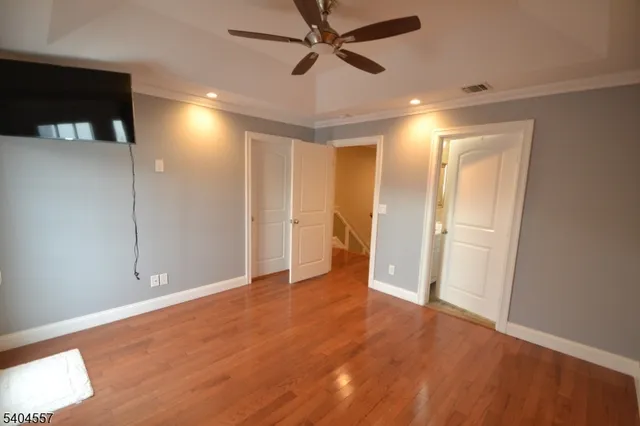 a view of empty room with wooden floor and fan