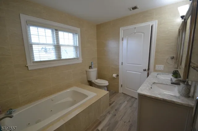 a bathroom with a granite countertop sink a toilet and bathtub