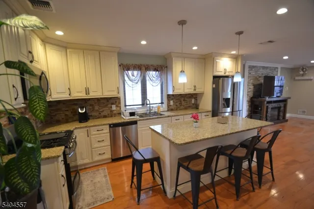 a kitchen with stainless steel appliances kitchen island granite countertop a table chairs sink and cabinets