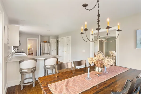 a dining room with wooden floor a chandelier a glass table and chairs