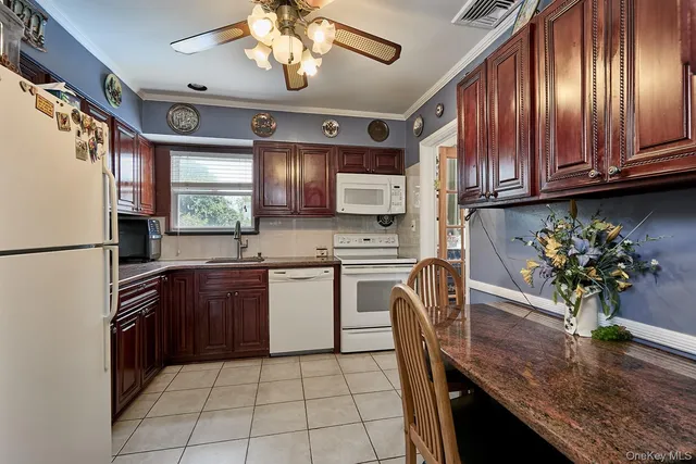 a kitchen with stainless steel appliances granite countertop a refrigerator a sink dishwasher a stove a dining table and chairs with wooden floor