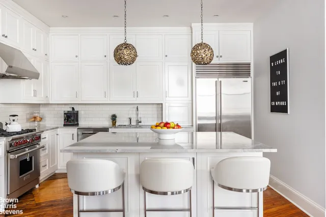 a kitchen with stainless steel appliances kitchen island granite countertop a sink a stove a dining table and chairs