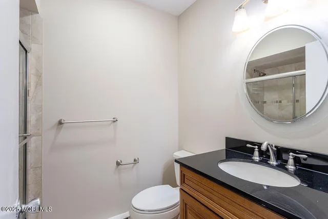 a bathroom with a granite countertop toilet a sink and mirror