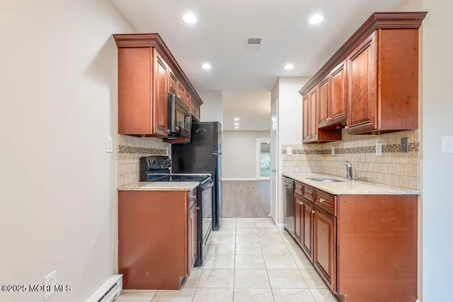 a kitchen with stainless steel appliances granite countertop a stove top oven a sink a refrigerator and cabinets