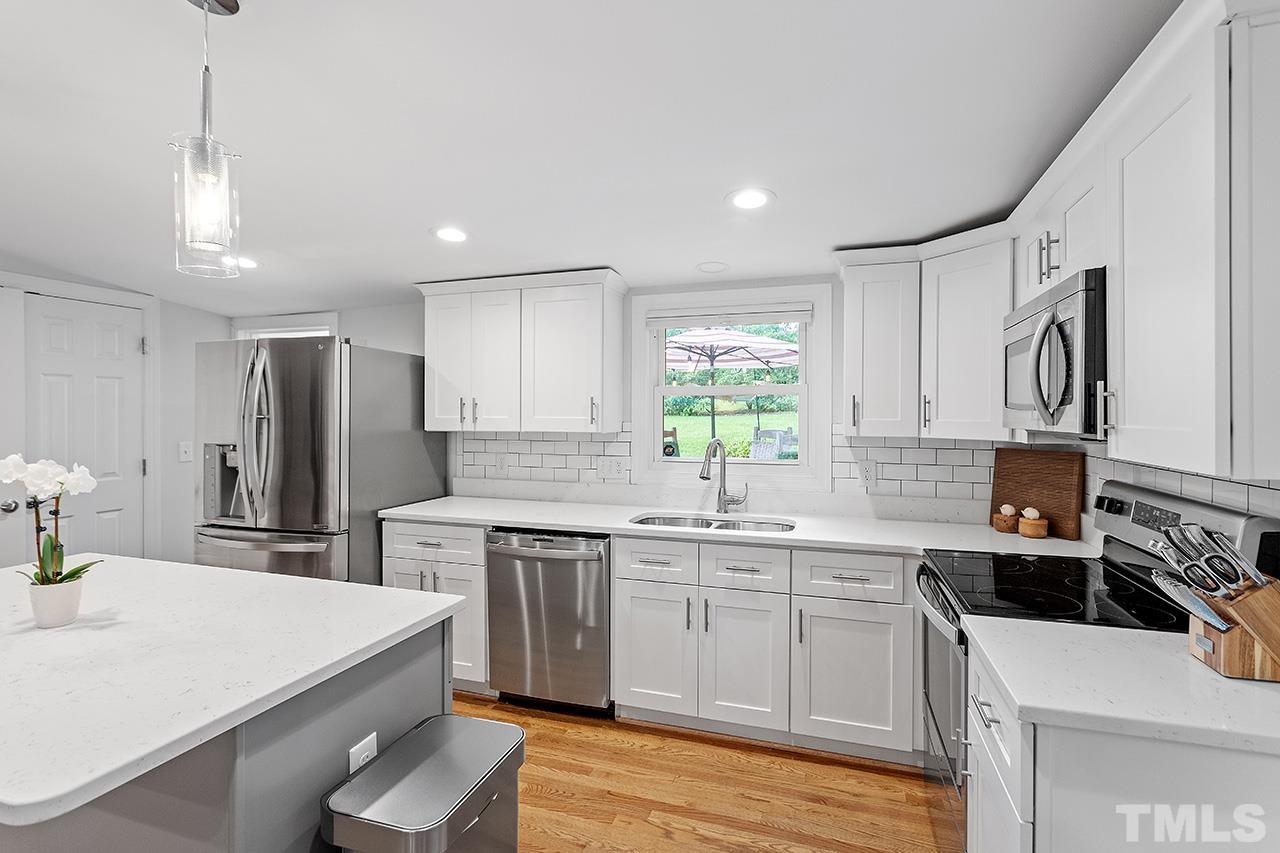 2214 Glascock Street Raleigh, NC 27610 - Photo 13 of 36 a kitchen with a sink a stove a refrigerator and white cabinets