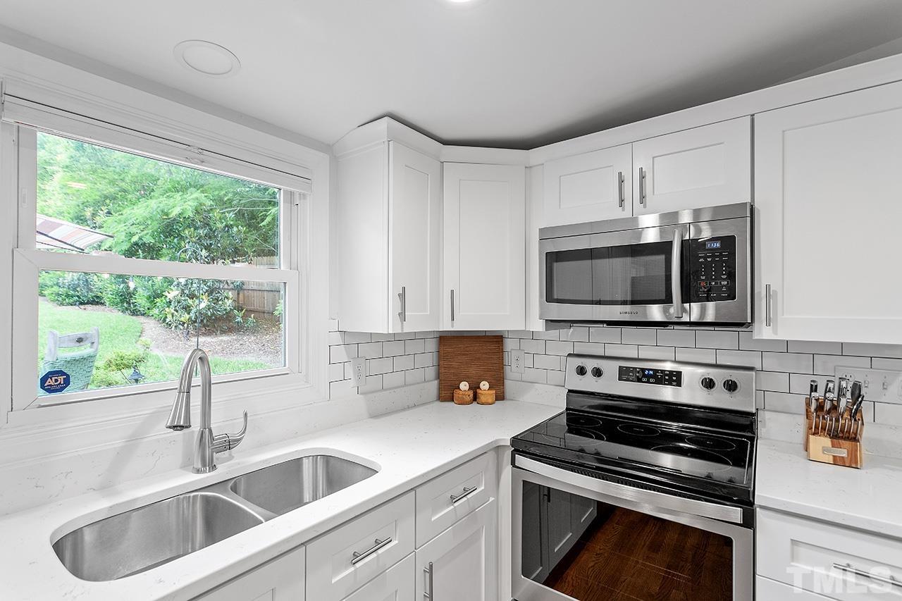 2214 Glascock Street Raleigh, NC 27610 - Photo 15 of 36 a kitchen with stainless steel appliances a stove a sink a microwave and cabinets