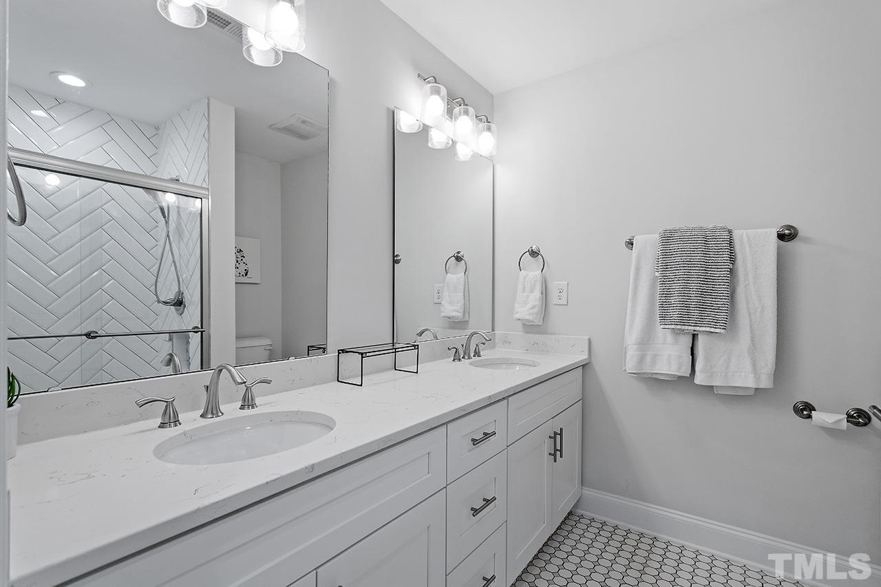 2214 Glascock Street Raleigh, NC 27610 - Photo 20 of 36 a bathroom with a double vanity sink a mirror and a shower