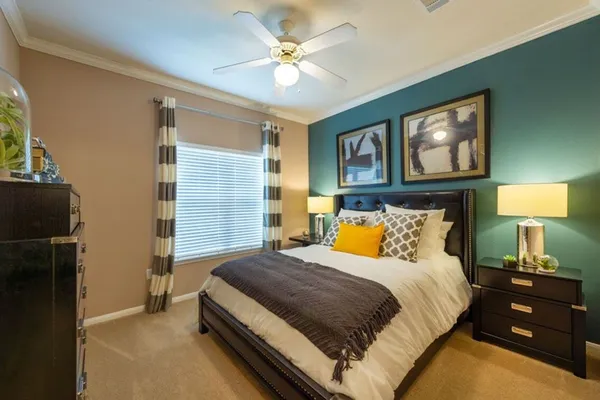 a bedroom with a bed and a lamp on dresser