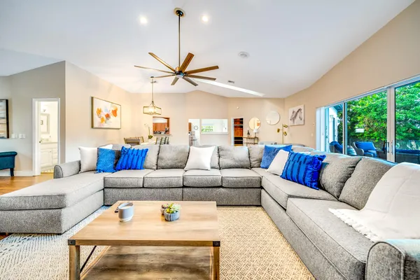 a living room with furniture a ceiling fan and a large window
