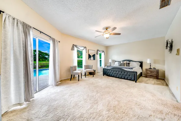 a spacious bedroom with a bed a chandelier and large window