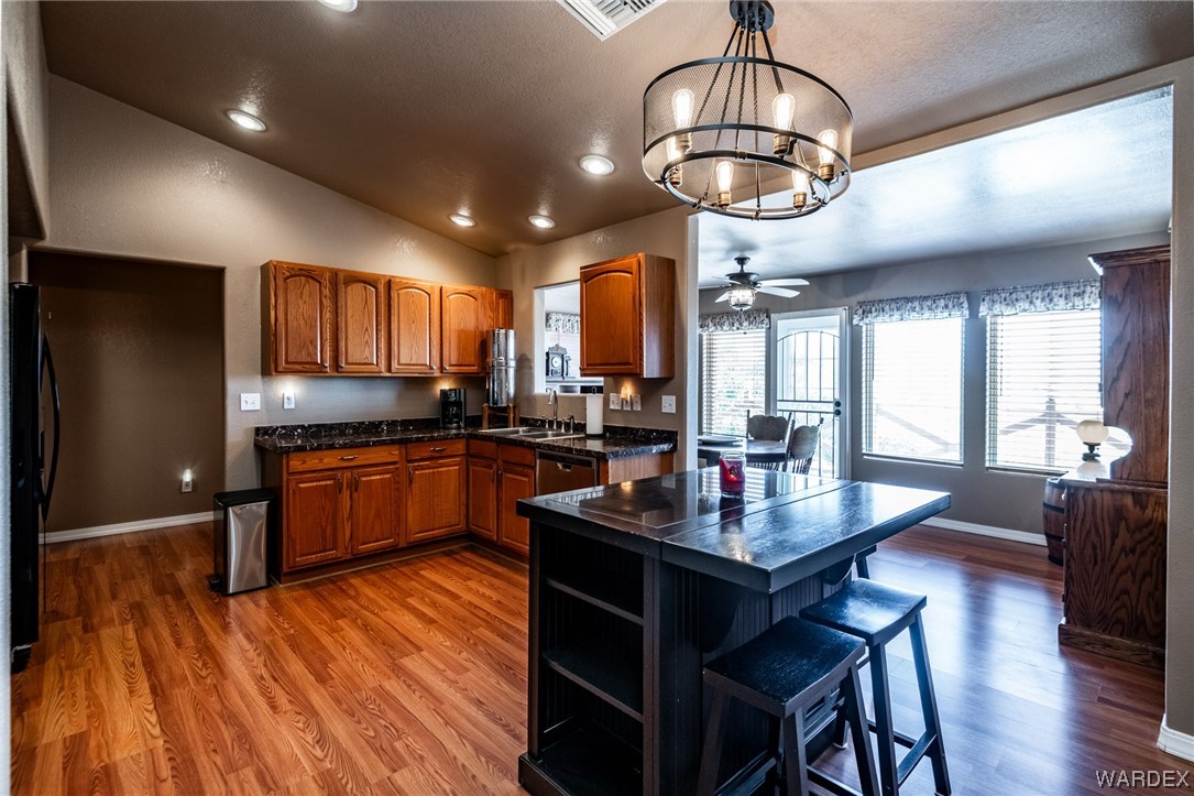 10363 East Blake Ranch Road Kingman, AZ 86401 - Photo 10 of 79 a kitchen with stainless steel appliances granite countertop a stove refrigerator a dining table and chairs with wooden floor