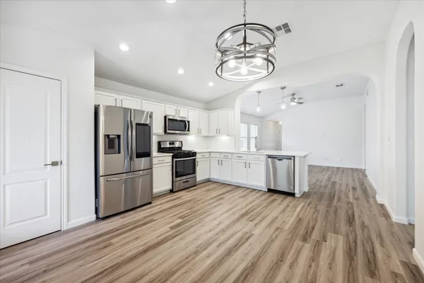 a large kitchen with cabinets wooden floor and stainless steel appliances
