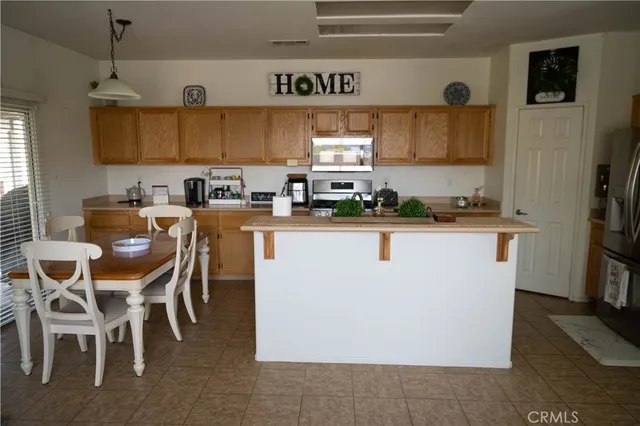 a kitchen with stainless steel appliances granite countertop a sink a stove a refrigerator cabinets and chairs