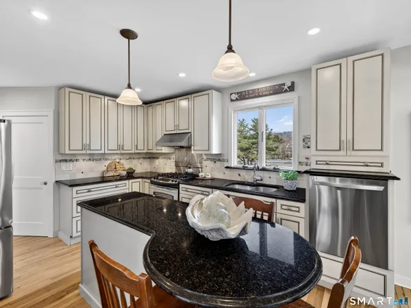 a kitchen with granite countertop kitchen island stainless steel appliances a stove a sink a dining table and chairs