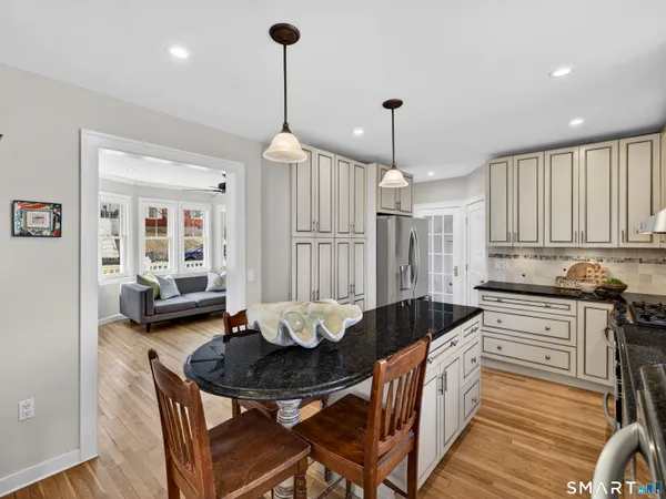 a kitchen with granite countertop a stove a sink and a white cabinets