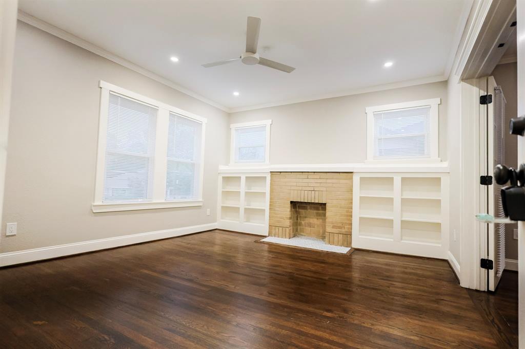 4114 Junius Street, Unit B Dallas, TX 75246 - Photo 4 of 13 an empty room with wooden floor fireplace and windows