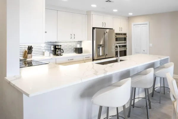 a kitchen with stainless steel appliances kitchen island granite countertop a kitchen island and chairs in it