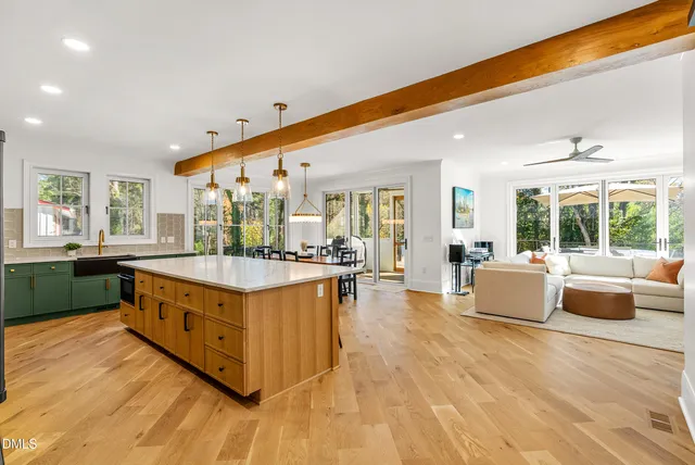 a kitchen with stainless steel appliances kitchen island granite countertop a refrigerator a stove a sink a dining table and chairs with wooden floor