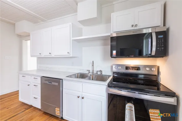 a kitchen with cabinets stainless steel appliances and wooden floor