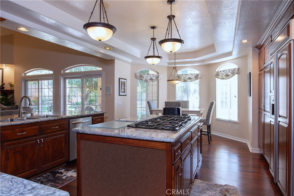 7361 Via Vista Riverside, CA 92506 - Photo 16 of 34 a kitchen with granite countertop a stove a sink dishwasher a dining table and chairs with wooden floor