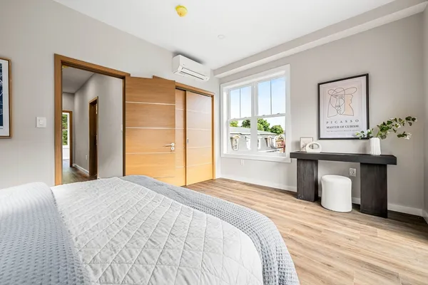 a bedroom with a bed and dresser with wooden floor