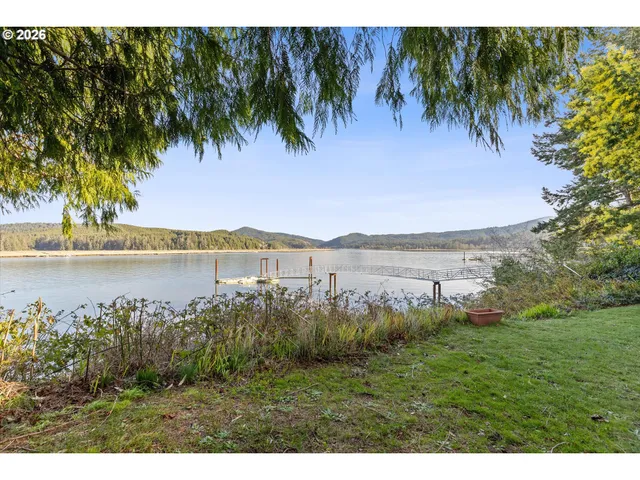a view of a lake with a yard and large trees