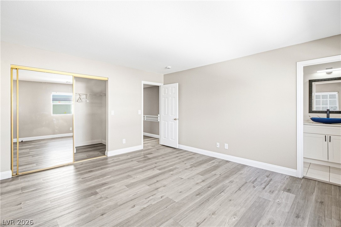 1475 Reef Ridge Court Las Vegas, NV 89128 - Photo 13 of 24 Clean lines and wood-look flooring define this comfortable bedroom featuring a mirrored closet.