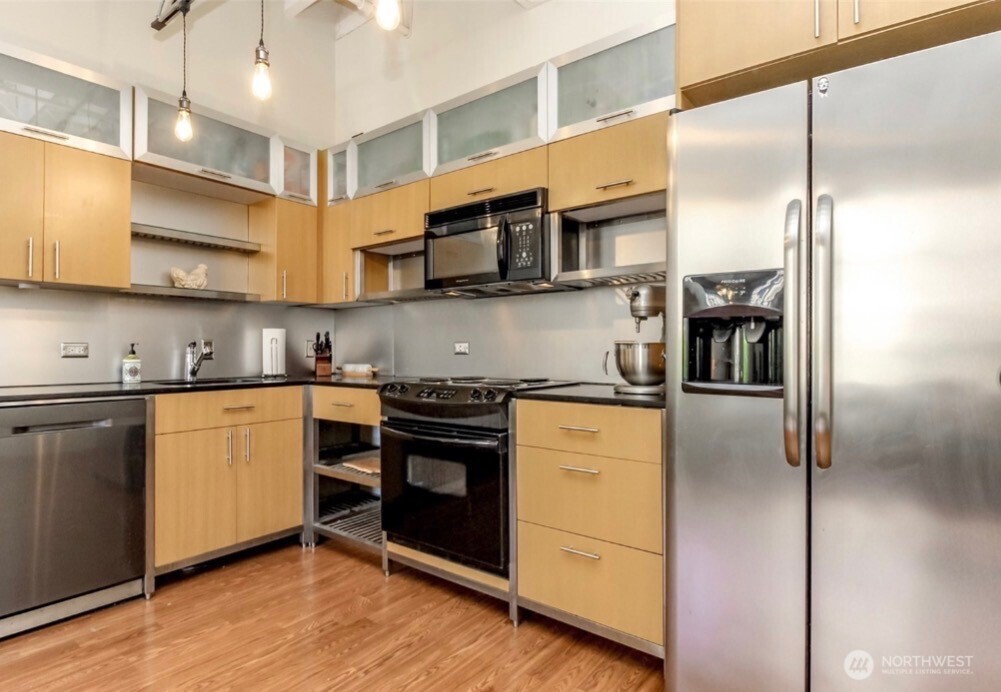 1120 Cliff Street, Unit 211 Tacoma, WA 98402 - Photo 7 of 20 a kitchen with stainless steel appliances granite countertop a refrigerator a stove and a sink with wooden floor