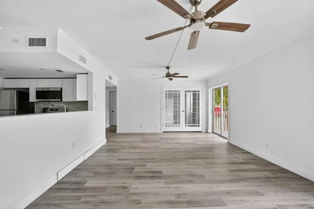 a view of a livingroom with a fireplace a ceiling fan and wooden floor
