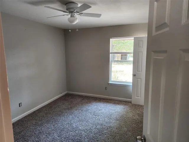 en empty room with windows and ceiling fan
