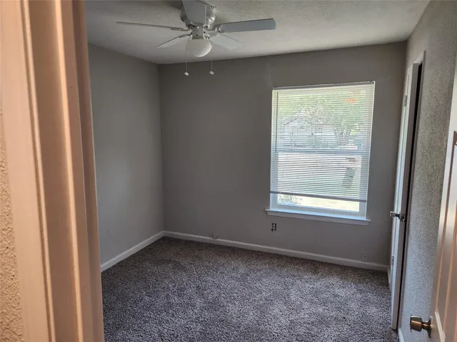 an empty room with a window and a fan